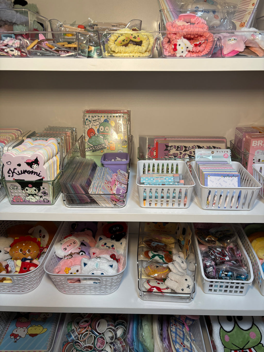 Closeup of store product including plush keychains, sticker sheets, notebooks, and notepads. 