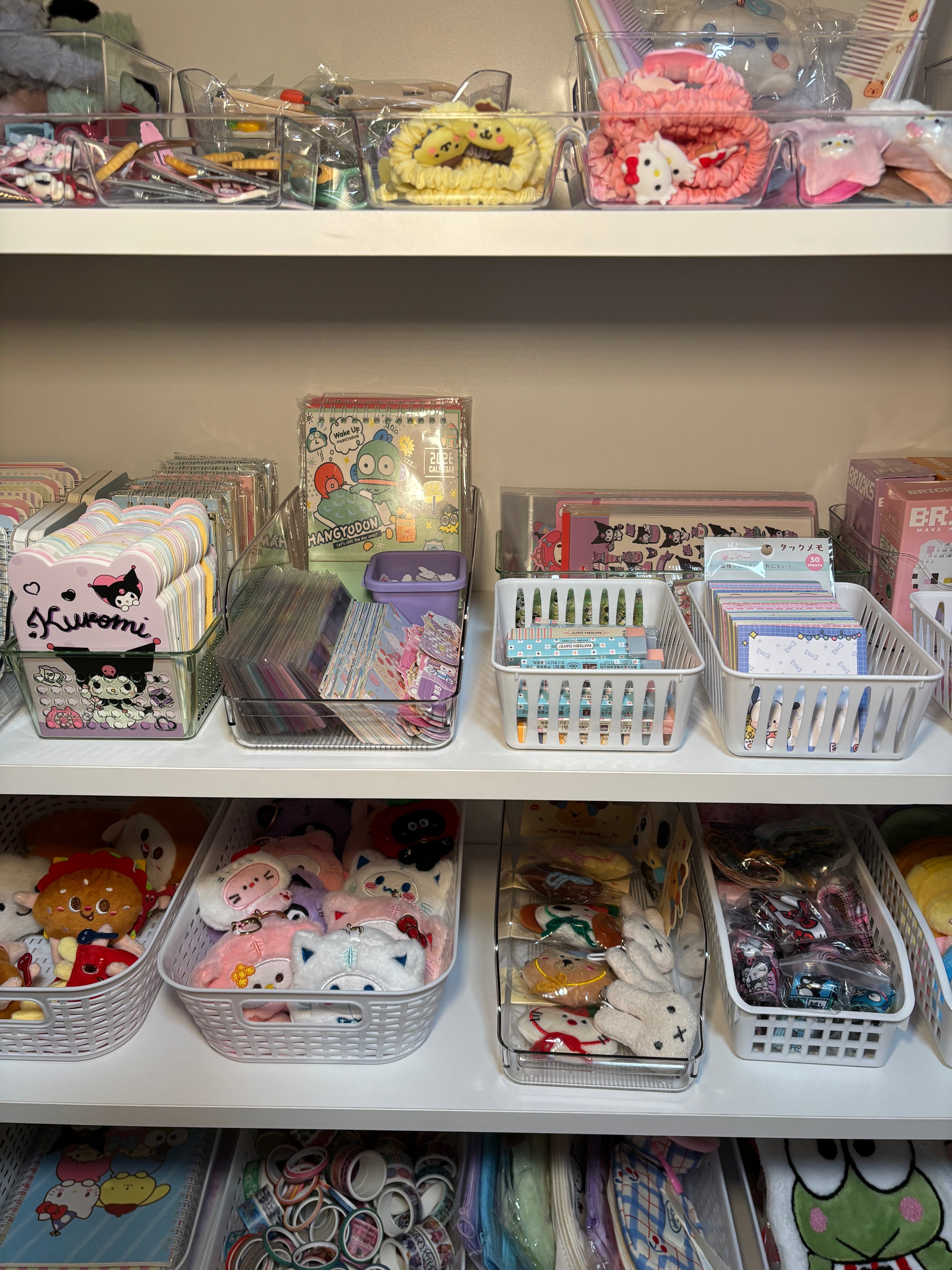 Closeup of store product including plush keychains, sticker sheets, notebooks, and notepads. 